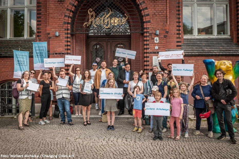 Viele Menschen der Kiezblock Initiativen Kaskel und Weitlingkiezmit Plakaten stehen vor dem Rathaus in Lichtenberg. Auf den Plakaten steht "Lebenswerte Straßen", "Sichere Schulwege", "Sichere Fußwege", "Bürger*innenbeteiligung", "Sichere Radwege" und "Nachhaltiger Verkehr"