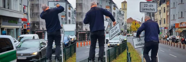 Ein Mensch auf einer Leiter, nimmt den Zusatz ""Luftreinhaltung"von einem Temp 30 Schild ab.